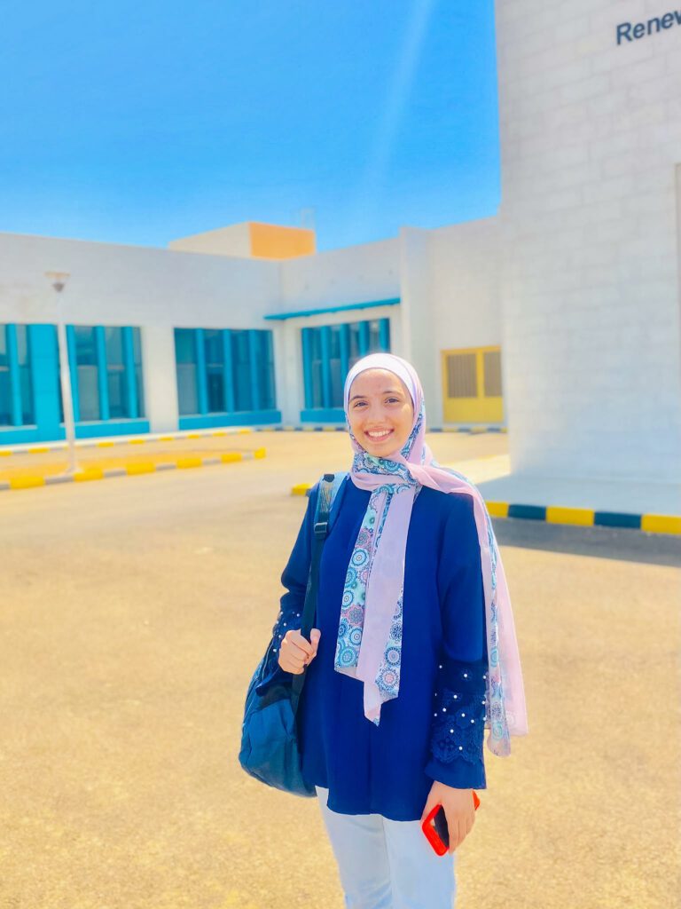 Mas TechGirl in front of a white school building with blue windows