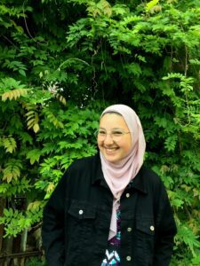 Youssra TechGirl in front of a vibrant green bush