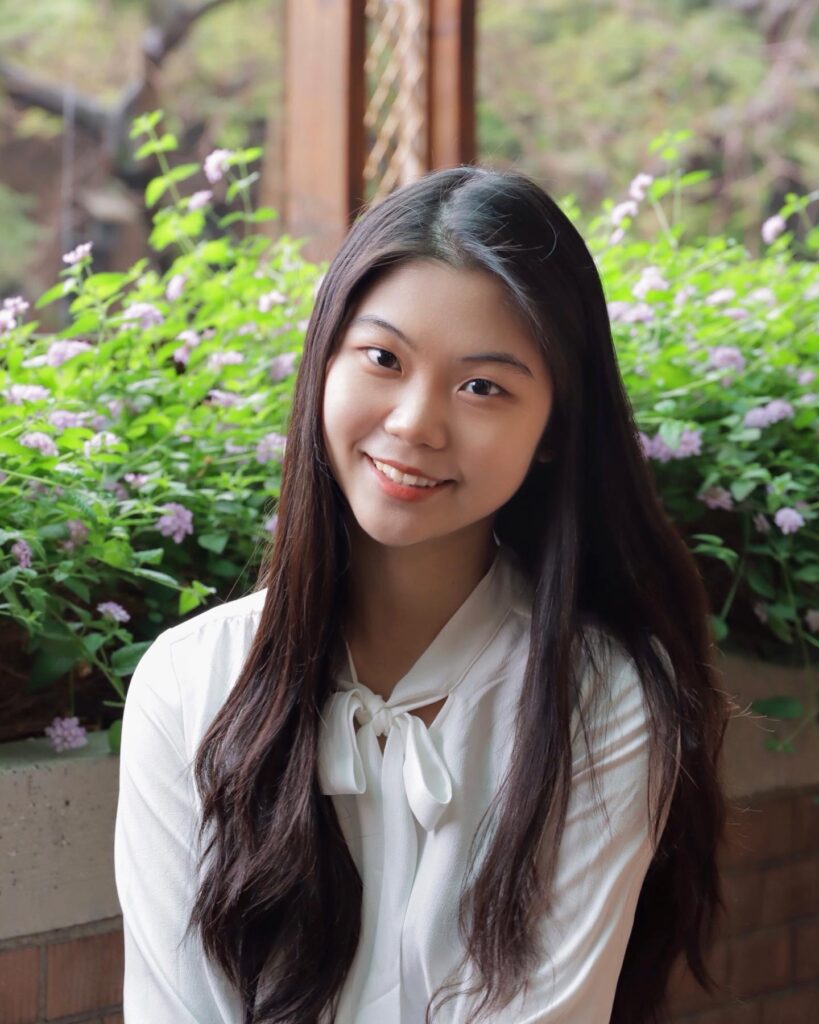 Grace is smiling with flowers behind her