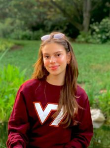 Luíza smiling in a field while wearing a Virginia Tech sweatshirt