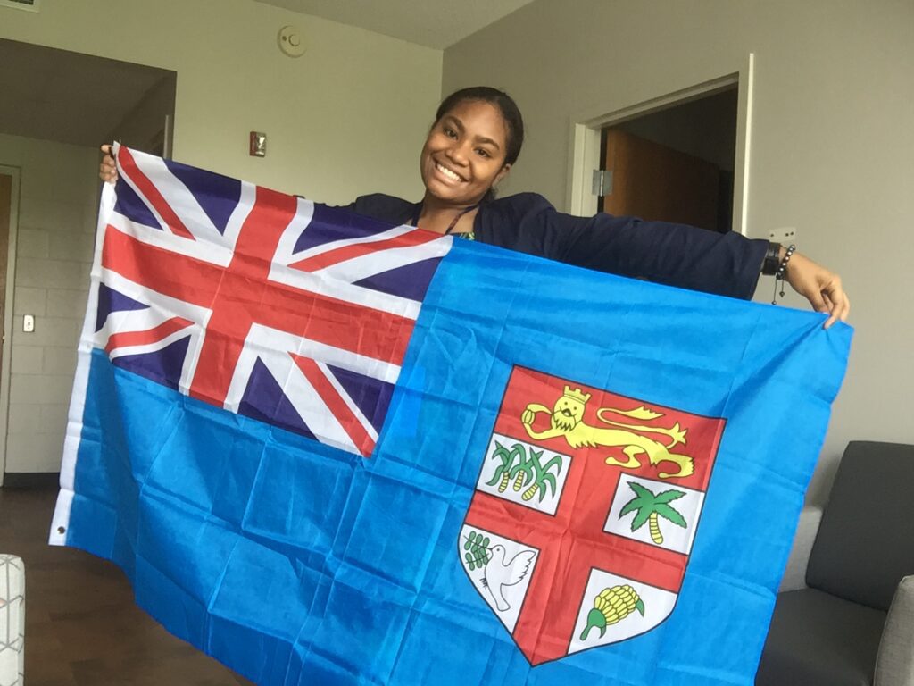 Esther smiles while holding Fijian flag across her body.