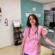 Rihab standing in veterinary clinic. She is wearing pink scrubs and a stethoscope around her neck.