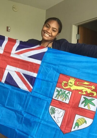 Esther smiles while holding Fijian flag across her body.