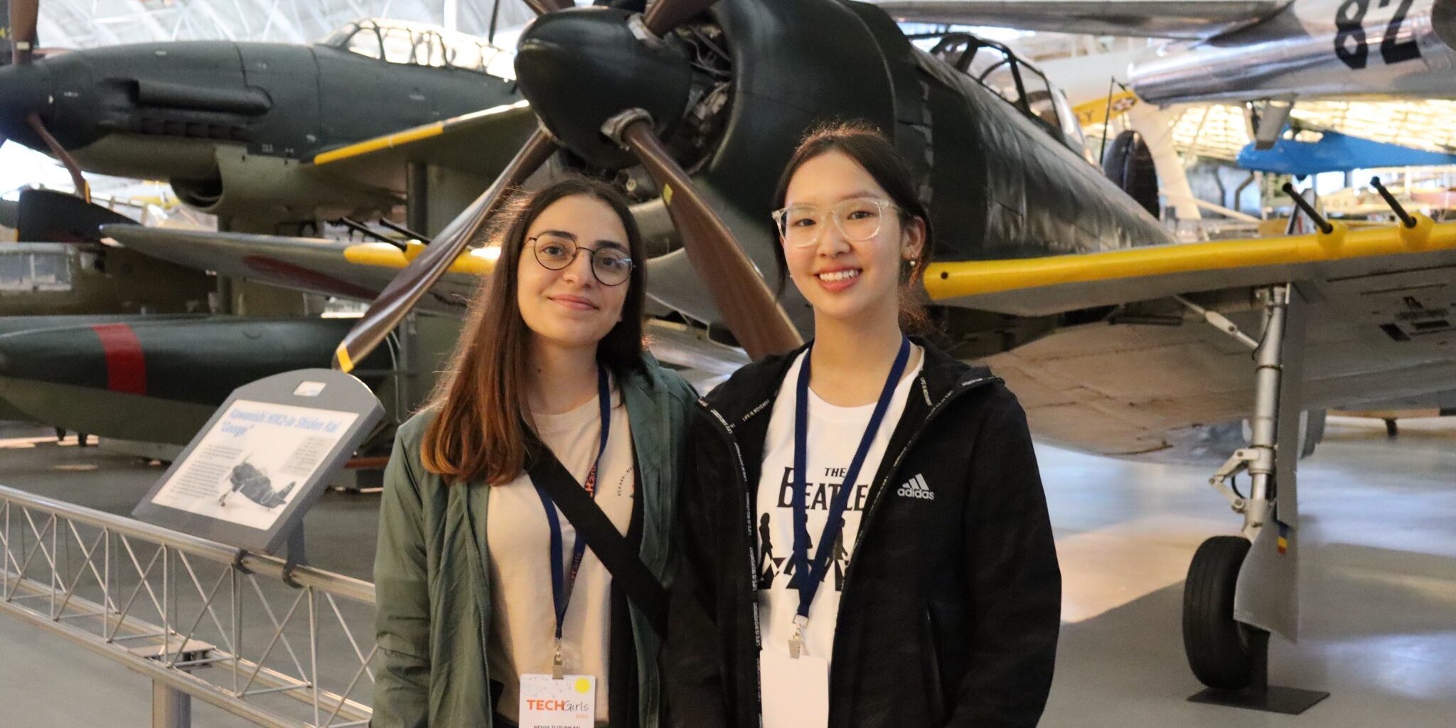 two girls standing in front of an airplane in a museum.