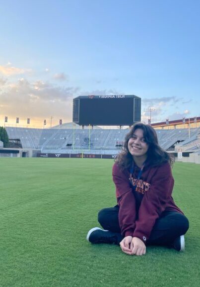 Stefania is seated on a field in a stadium